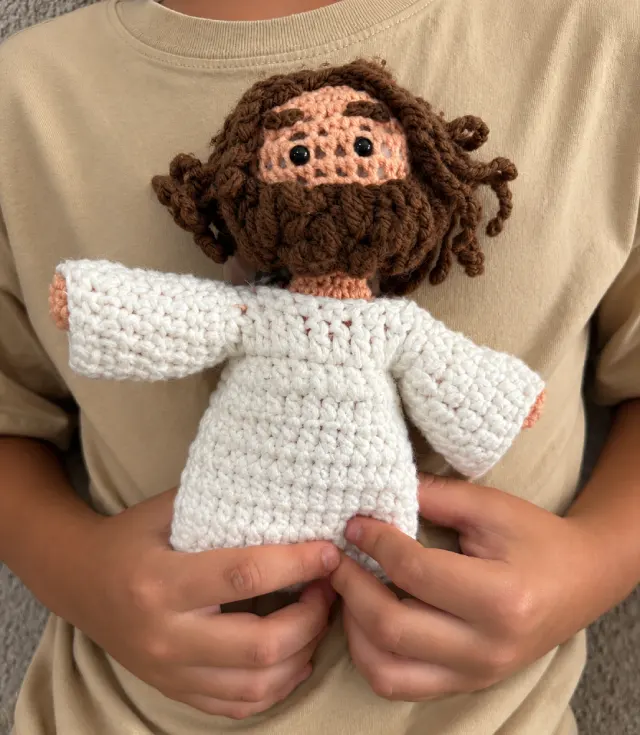 A child holding the crocheted Jesus plush